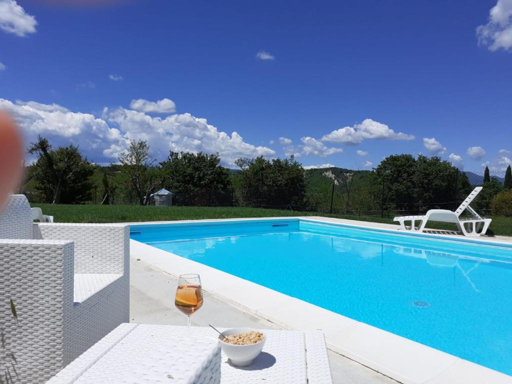 una piscina con una copa de vino y 2 sillas en Casale Il Ventaglio, en Ficulle