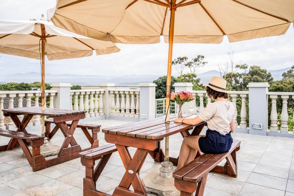 a woman sitting at a picnic table under an umbrella at Avemore Sedgefield in Sedgefield