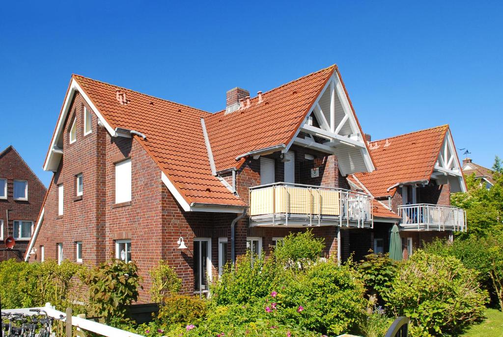 une grande maison en briques avec un toit rouge dans l'établissement Ferienwohnung de Vries, à Langeoog