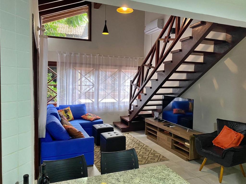 a living room with a blue couch and a staircase at Apartamento com varanda em frente a Praia de Maresias in São Sebastião