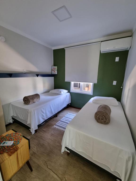 twee bedden in een kamer met groene muren bij Parada Vale Europeu - Timbó SC in Timbó