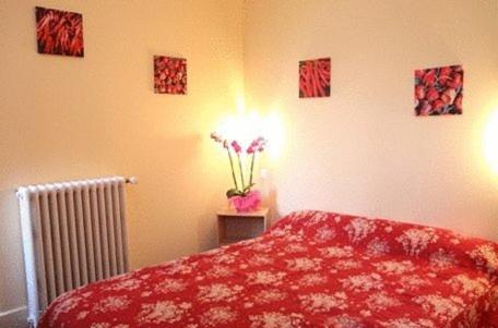 a bedroom with a red bed and a vase of flowers at Logis Hotel Le Clos Des Oliviers in Bourg-Saint-Andéol