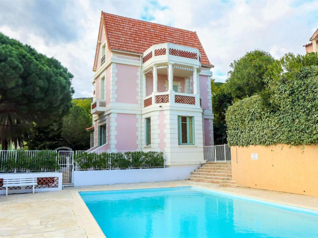 una casa rosa con piscina frente a ella en Apartment Castel Haussmann-1 by Interhome en Cavalaire-sur-Mer