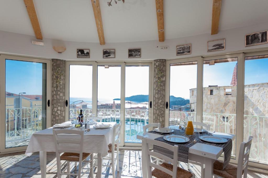 a dining room with white tables and chairs and windows at Spa Resort Luxury Apartments in Budva