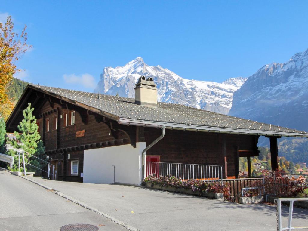 a building with a snow covered mountain in the background at Apartment Chalet Shangri La by Interhome in Grindelwald