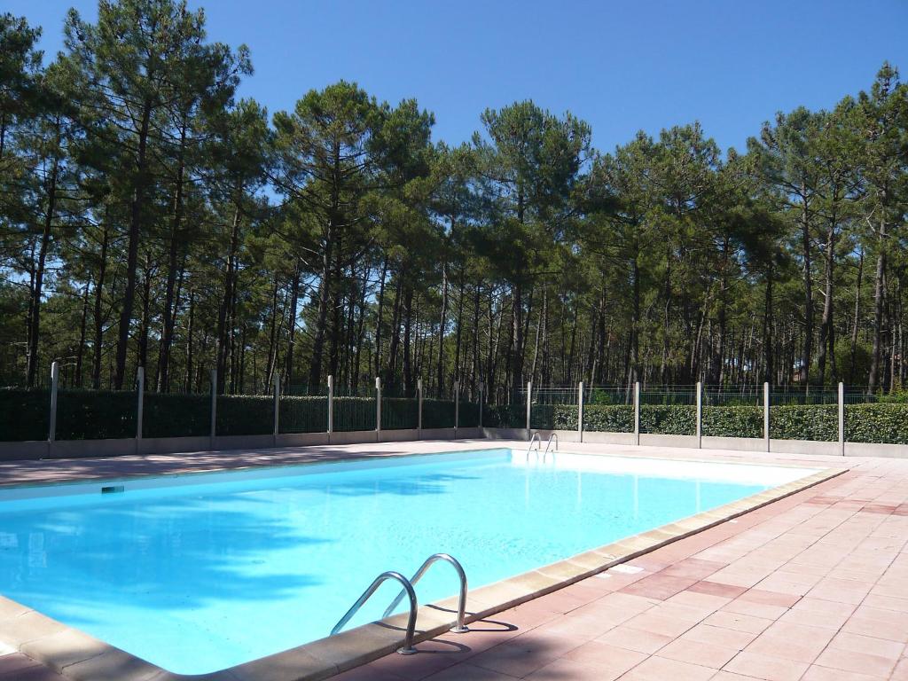a large blue swimming pool with trees in the background at Holiday Home Les Palombes-7 by Interhome in Lacanau-Océan