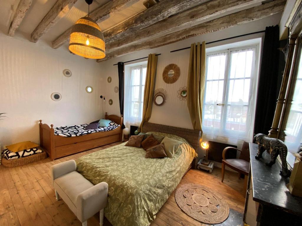 - une chambre avec un lit, une chaise et des fenêtres dans l'établissement Les petites Mirabelles, à Noyers-sur-Cher