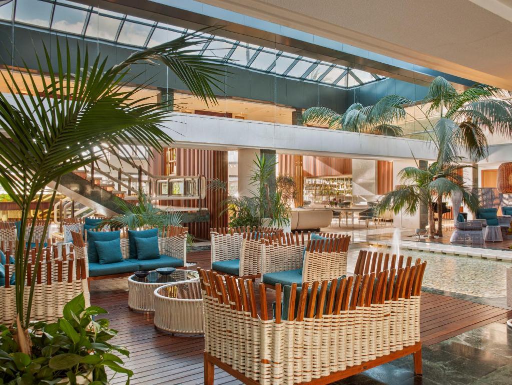 a lobby with tables and chairs and palm trees at Hotel Don Pepe Gran Meliá in Marbella