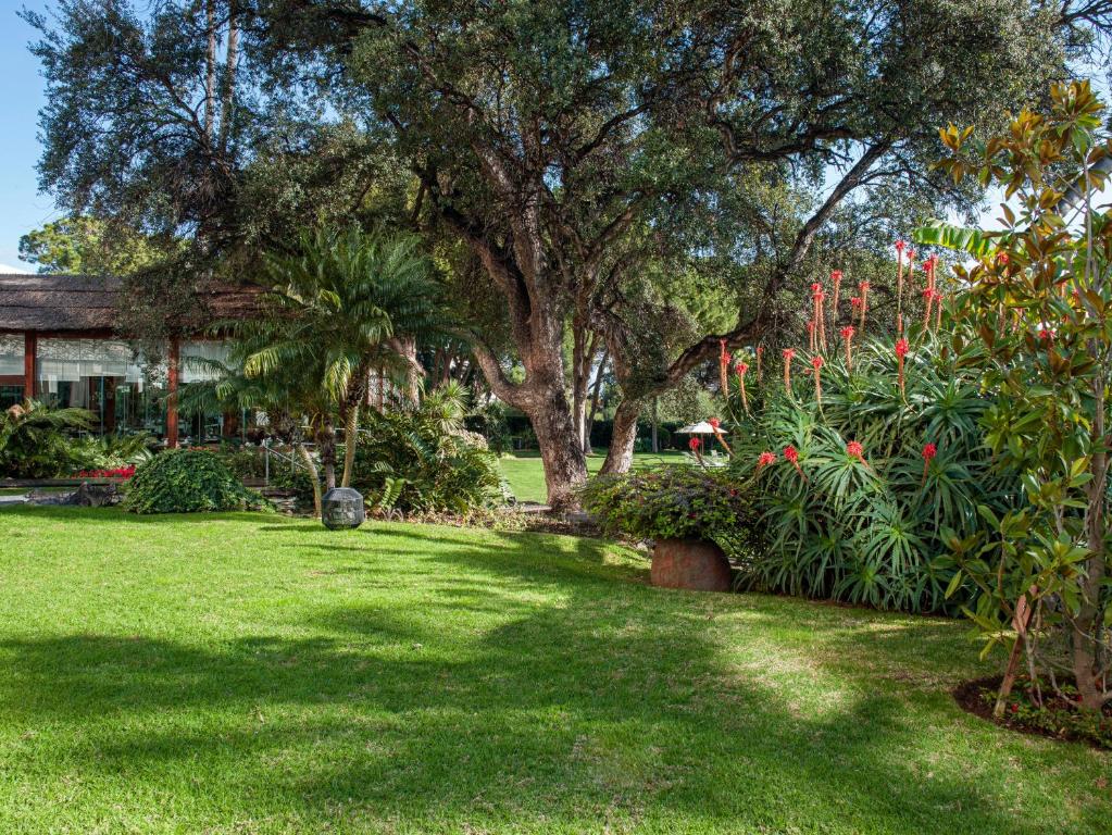 a yard with a large tree and some flowers at Hotel Don Pepe Gran Meliá in Marbella