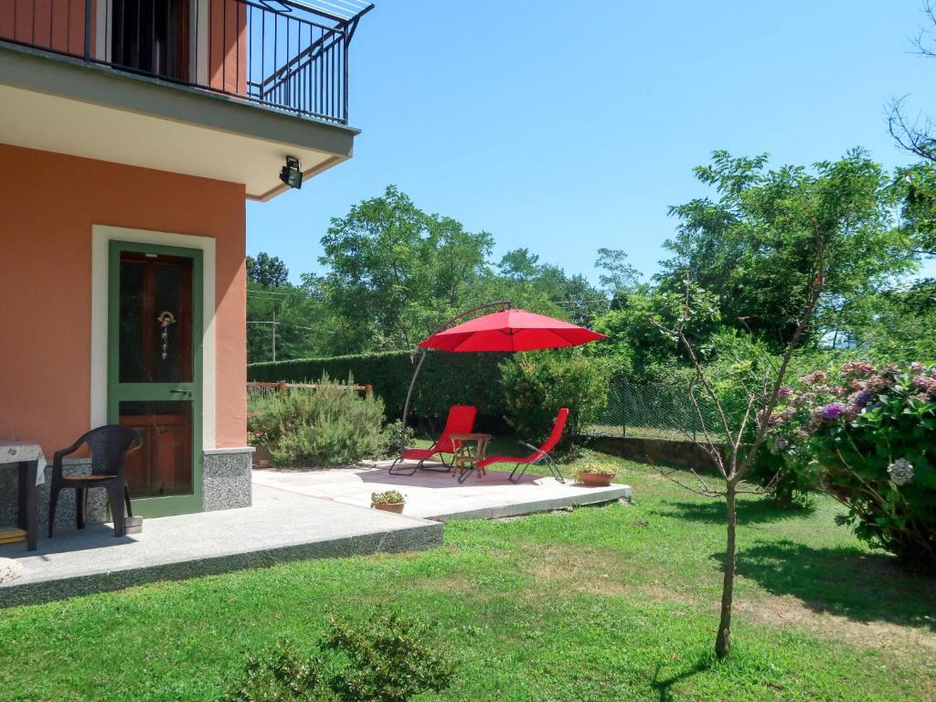 un patio con 2 sillas y una sombrilla roja en Apartment Casa dei Fiori by Interhome en Mergozzo