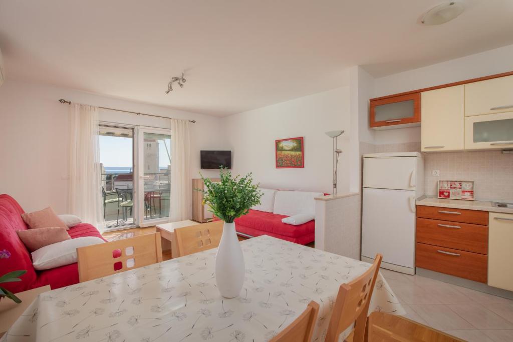 a kitchen and living room with a table with a vase of flowers at Apartment Sunce in Promajna