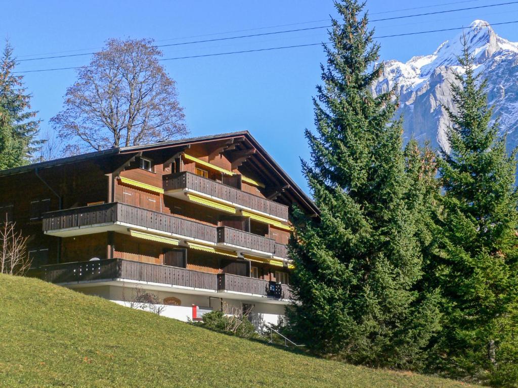 a building on a hill with mountains in the background at Apartment Bodmisunne by Interhome in Grindelwald