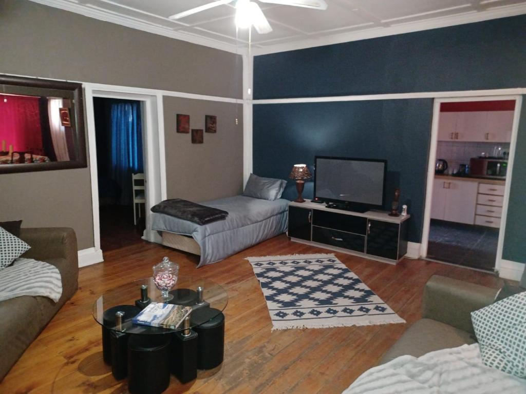 a living room with a couch and a tv at Karoo Refresh Cheerful 2 Bedroom House in Oudtshoorn
