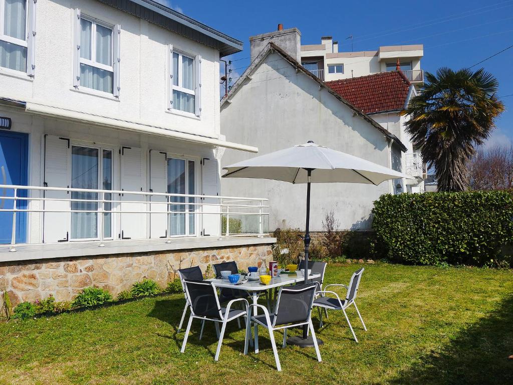 uma mesa e cadeiras com um guarda-sol num quintal em Holiday Home La Coloniale by Interhome em Auray