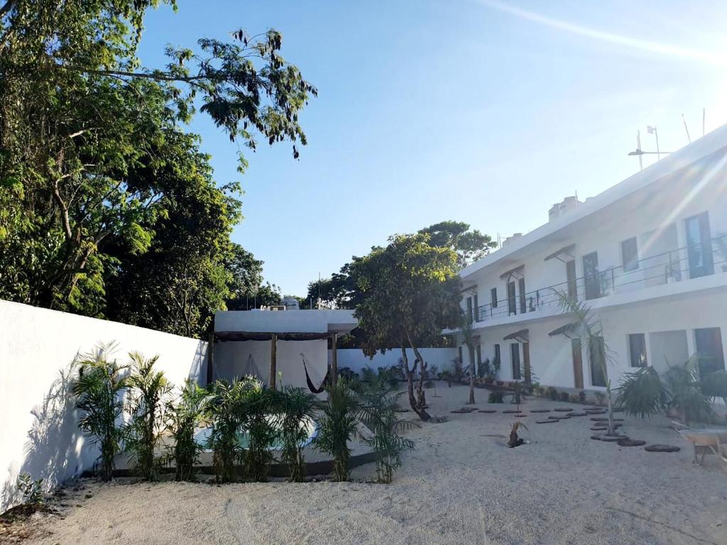 a white house with a white wall and trees at Villas Chital Bacalar in Bacalar