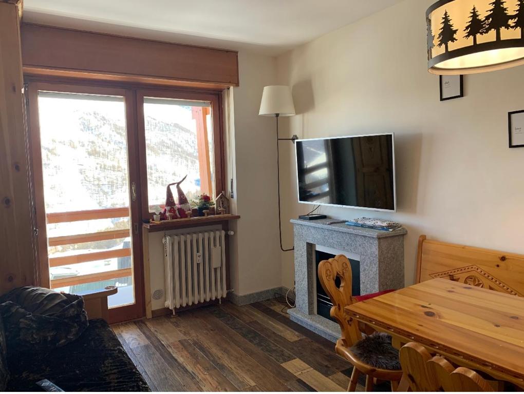 salon z telewizorem i kominkiem w obiekcie Bilocale con vista a Sestriere w mieście Sestriere