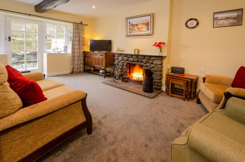 a living room with two couches and a fireplace at 2 Bridge Syke, Elterwater in Chapel Stile