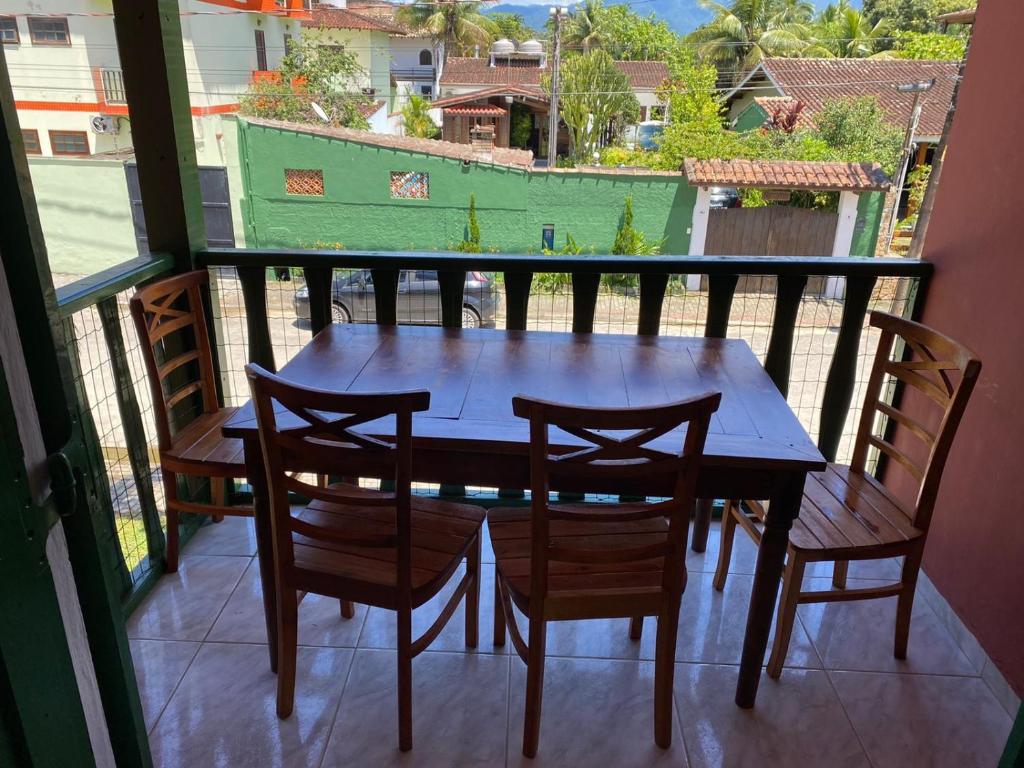 y balcón con mesa y sillas de madera. en Chalés Sol da Ribeira, en Ubatuba