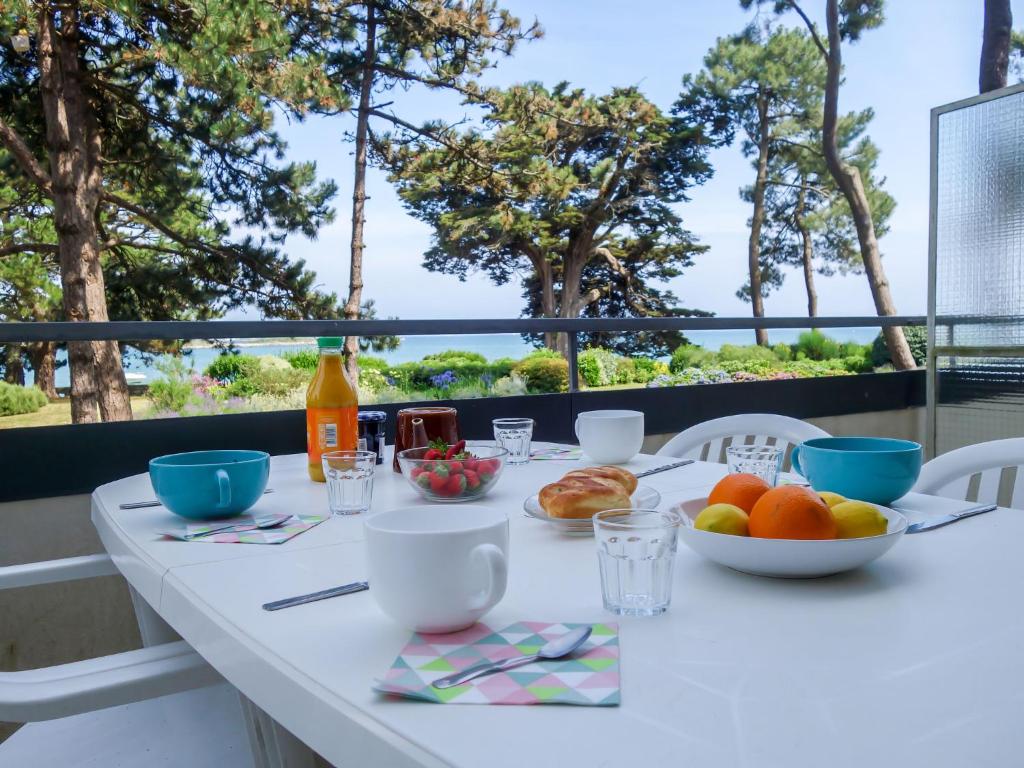 una mesa con comida y bebida en un balcón con árboles en Apartment Baie de Beaumer-1 by Interhome, en Carnac