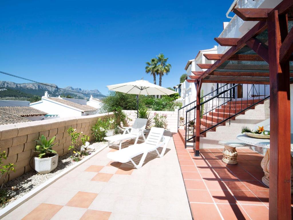 Un patio con dos sillas blancas y una sombrilla. en Holiday Home Yona by Interhome, en Empedrola