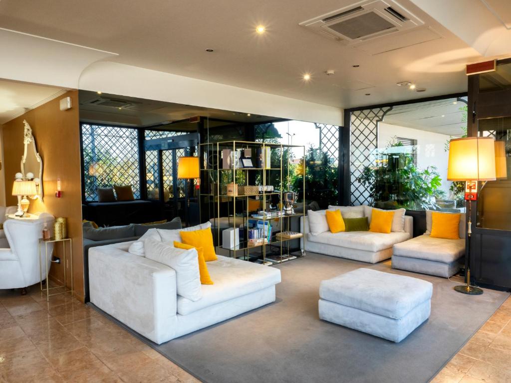 sala de estar con 2 sofás blancos y almohadas amarillas en Hotel Europa, en Palazzolo sullʼOglio