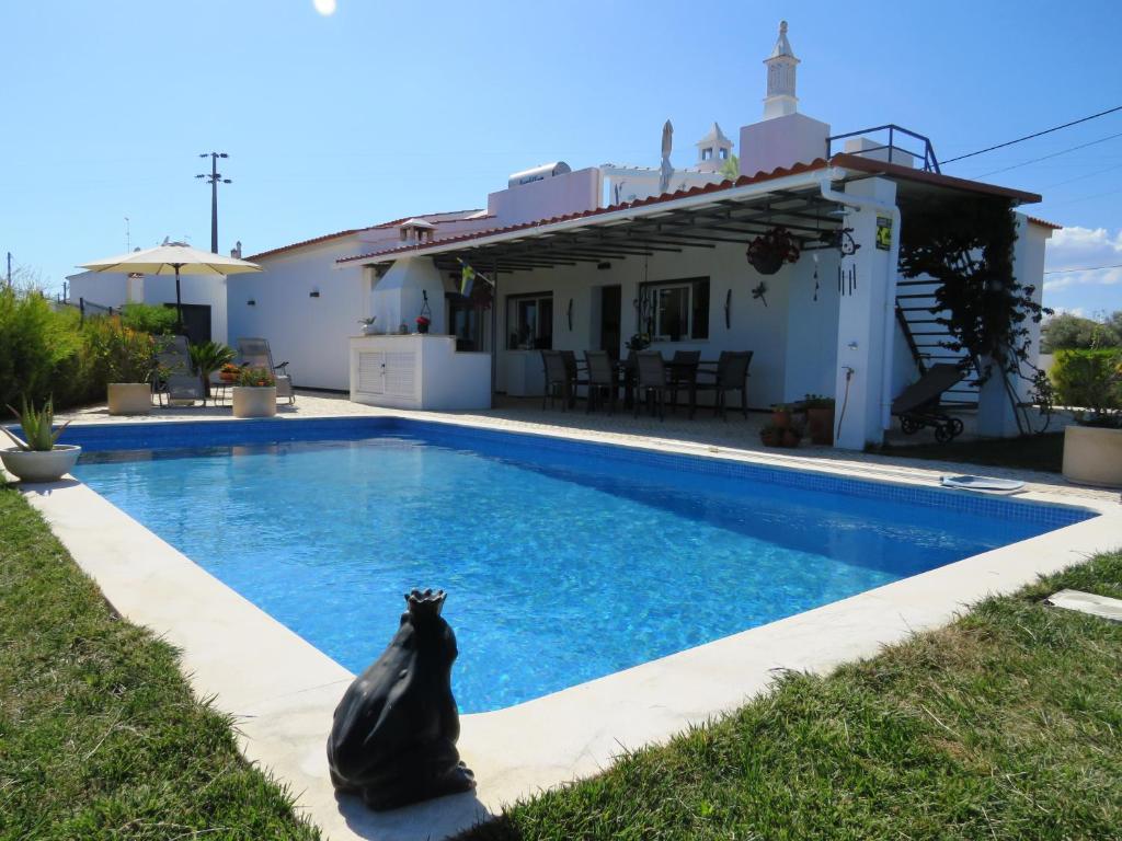 un chat noir assis au bord d'une piscine dans l'établissement Casa Nokleby - Moradia com Piscina Privada e Jardim, à Altura