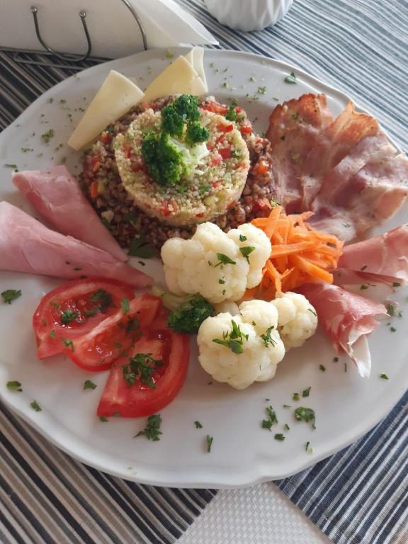 a white plate of food with vegetables and meat at Spa Resort Luxury Apartments in Budva