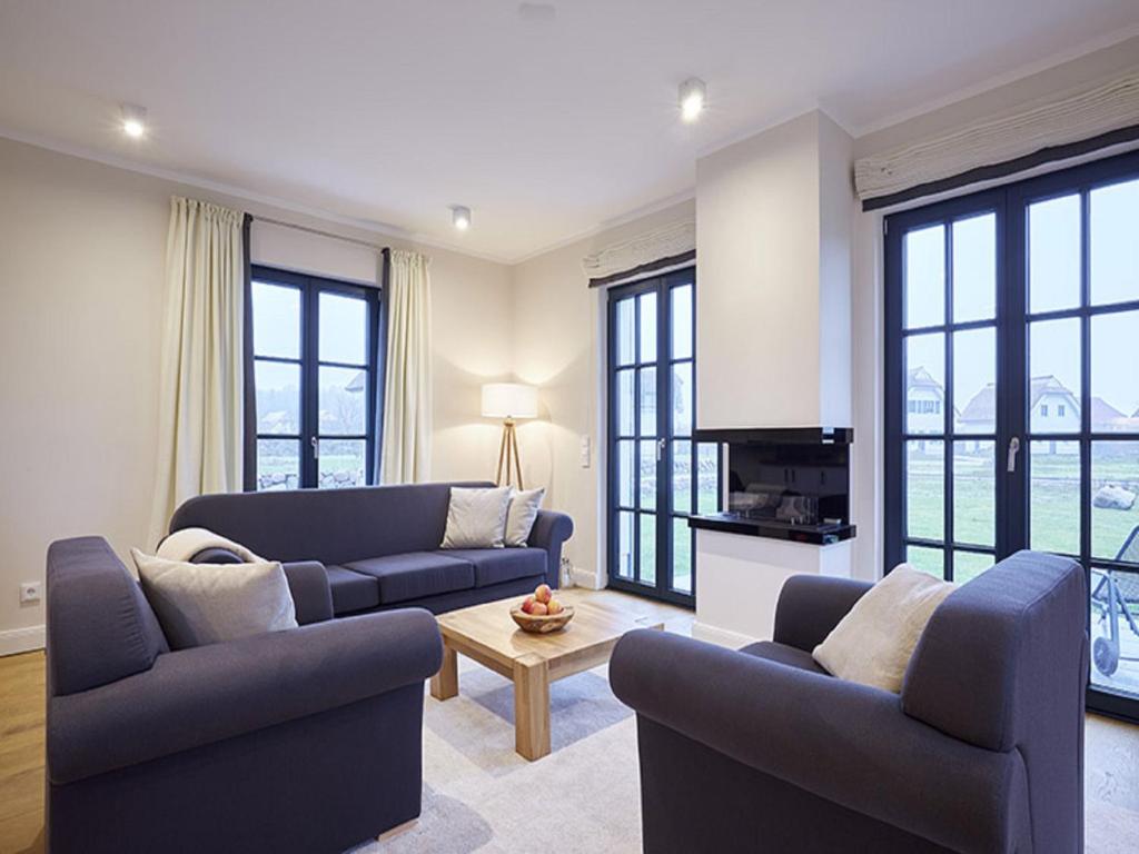 a living room with two couches and a table at Reetland am Meer - Superior Reetdachvilla mit 2 Schlafzimmern, Kamin und 2 Terrassen F17 in Dranske