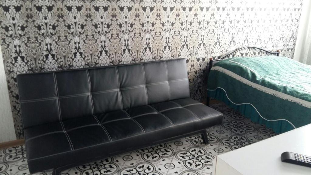a black leather couch in a room with a bed at Морской бриз in Odesa