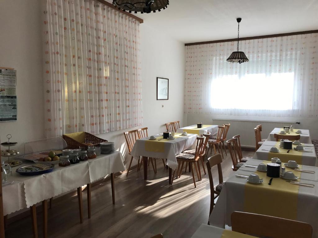 ein Esszimmer mit Tischen, Stühlen und einem Fenster in der Unterkunft Gästehaus & Weingut Klein in Illmitz