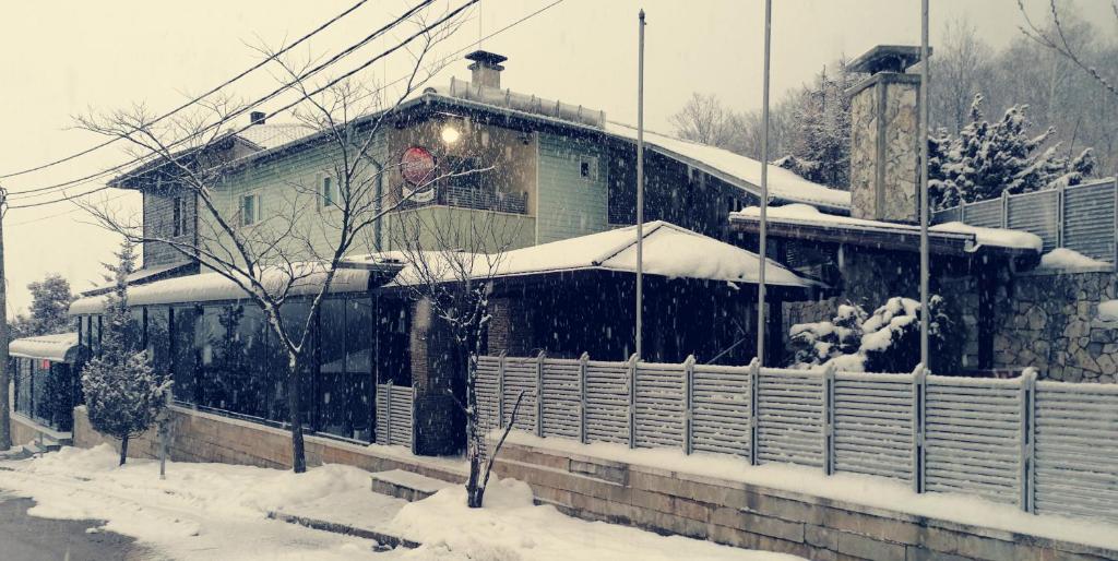 una casa cubierta de nieve delante en Discret Hotel & Restaurant en Vladaya