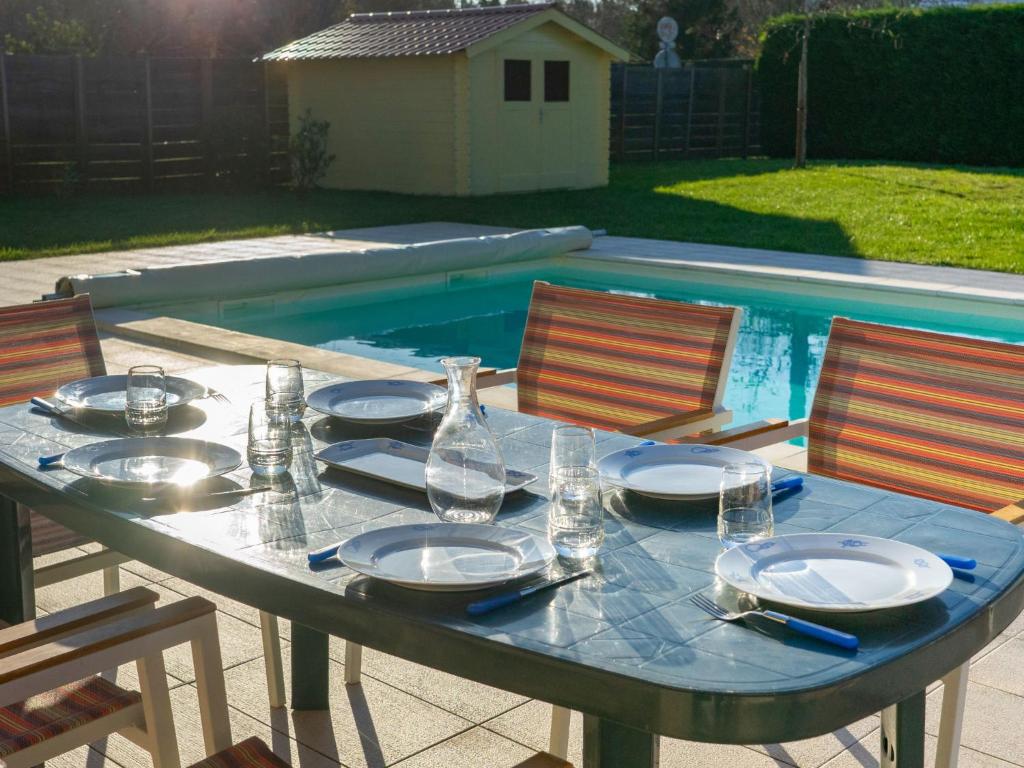 a table with plates and glasses on it next to a pool at Holiday Home Philibert by Interhome in Carcans