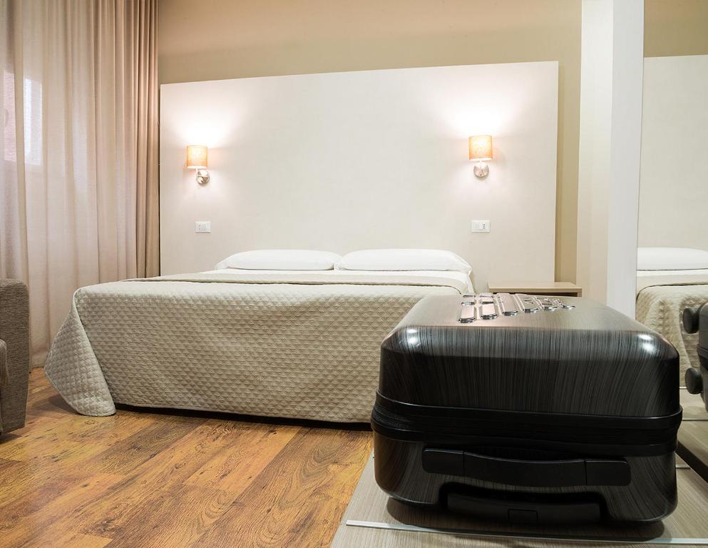 ein Hotelzimmer mit einem Bett und einem Koffer auf dem Boden in der Unterkunft B&B Erifrà Piccolo Hotel in Cosenza