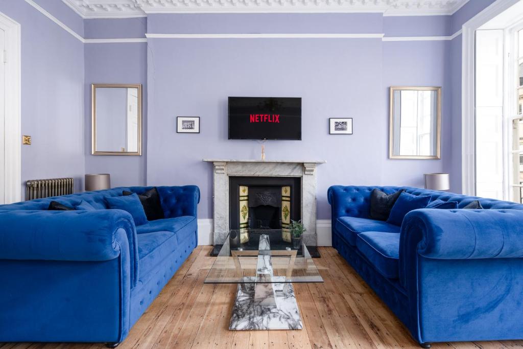 a living room with blue couches and a fireplace at Darcys' View in Bath