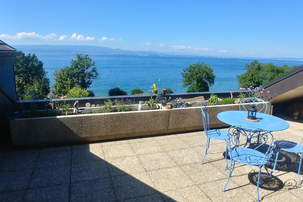 un patio con mesa, sillas y el océano en Lakefront. Appartement pieds dans l'eau. View and direct access to the lake., en Anthy