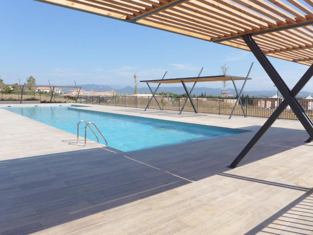 a large swimming pool with a wooden deck and a wooden pergola at Apartment Royal Green by Interhome in Roquebrune-sur-Argens
