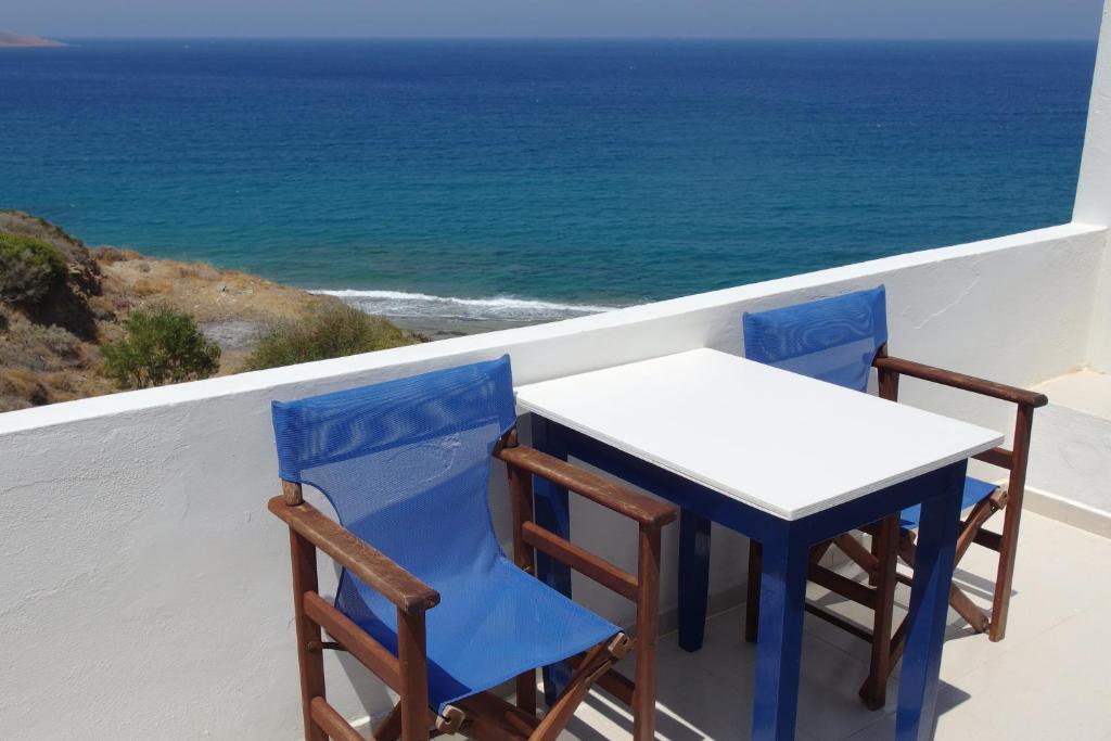 two chairs and a table on a balcony with the ocean at Ploimon Apartments in Sitia