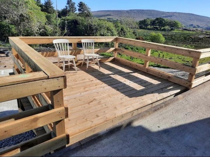 a wooden deck with two chairs and a fence at The Villa in Lettermacaward