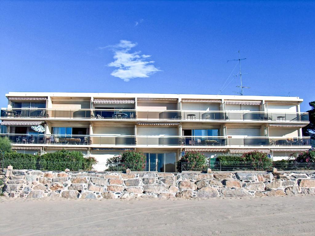 a large building on the beach next to a stone wall at Studio De la Plage-3 by Interhome in Cavalaire-sur-Mer