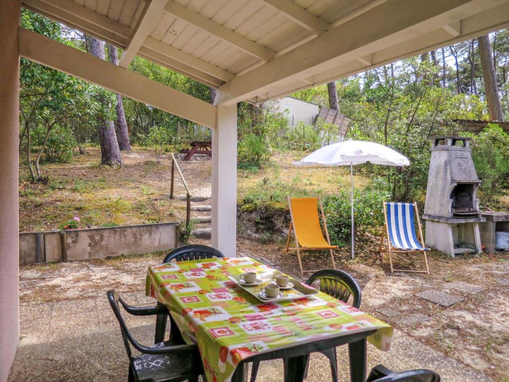 einen Tisch mit Stühlen und einem Sonnenschirm auf einer Terrasse in der Unterkunft Holiday Home Lac et forêt by Interhome in Lacanau