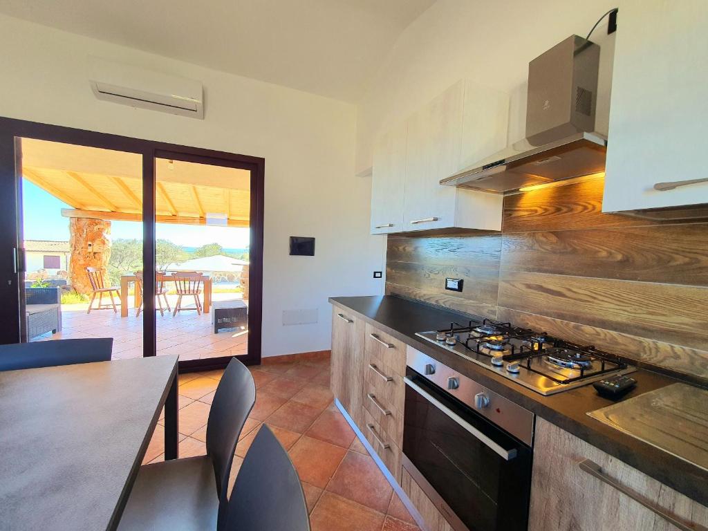 uma cozinha com fogão forno superior ao lado de uma mesa em Villini Cortesas em Orosei
