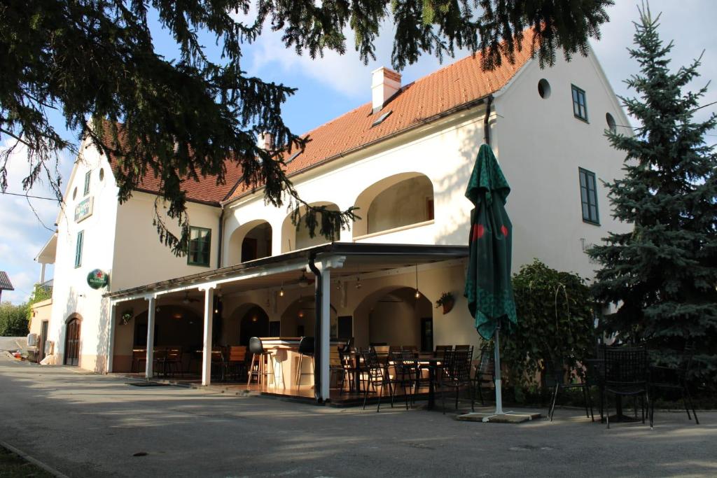 ein Gebäude mit Tischen, Stühlen und einem Regenschirm in der Unterkunft Taverna 1860 Rooms & Apartments in Donja Zelina
