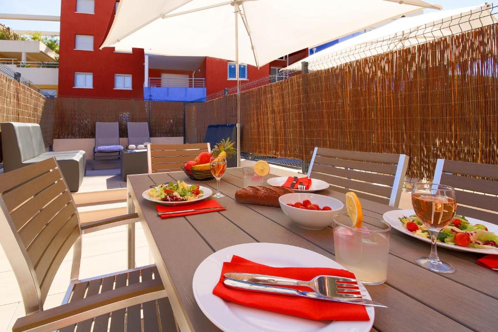 une table en bois avec des assiettes de nourriture sur une terrasse dans l'établissement SELECT'SO HOME - Résidence Le Poséidon - Mazet en Duplex - Prestations de qualité & Services Hôteliers - POS-D, à Bormes-les-Mimosas