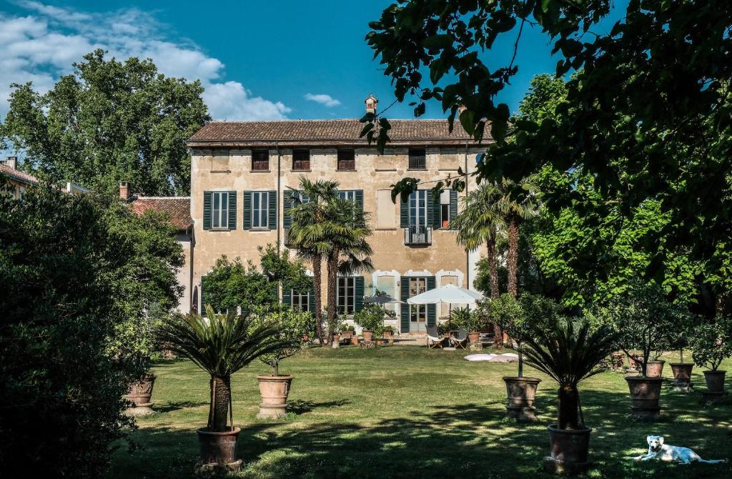 ein großes Haus mit Palmen im Hof in der Unterkunft Bed and Breakfast Locanda Lugagnano in Cassinetta di Lugagnano