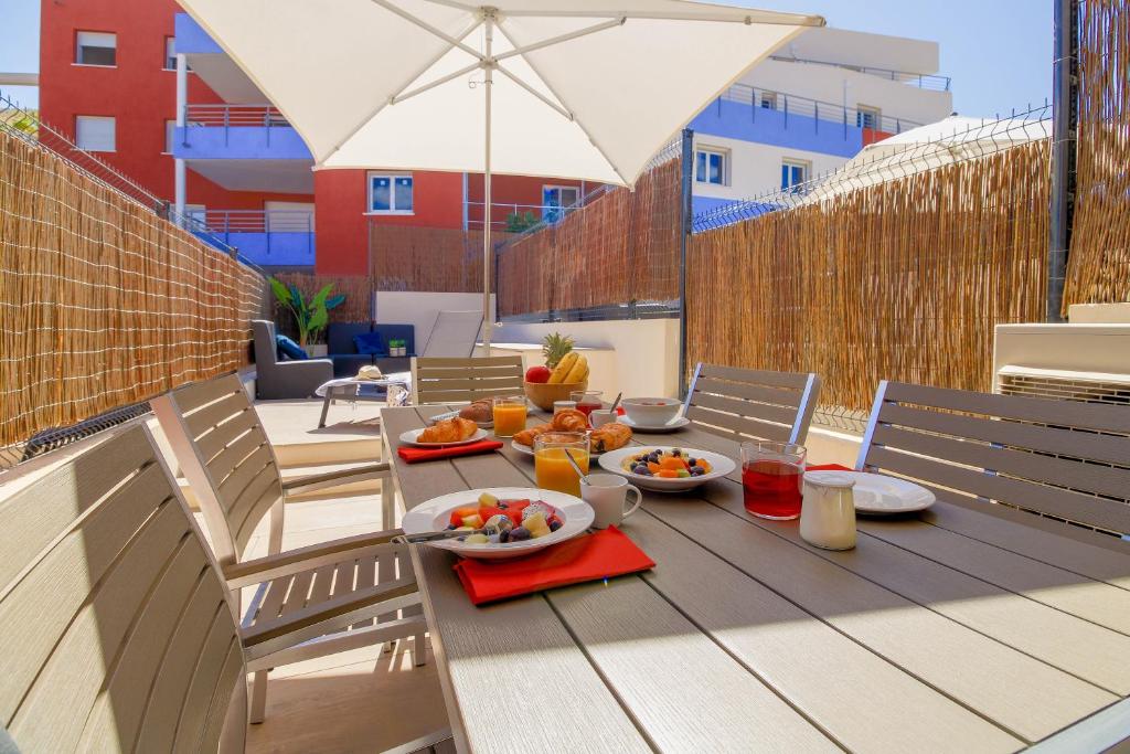 einen Tisch mit Essen auf einer Terrasse in der Unterkunft SELECT'SO HOME - Résidence Le Poséidon - Mazet en Duplex pour 6 personnes - Piscine, Parking privé - Services hôteliers - POS-B in Bormes-les-Mimosas