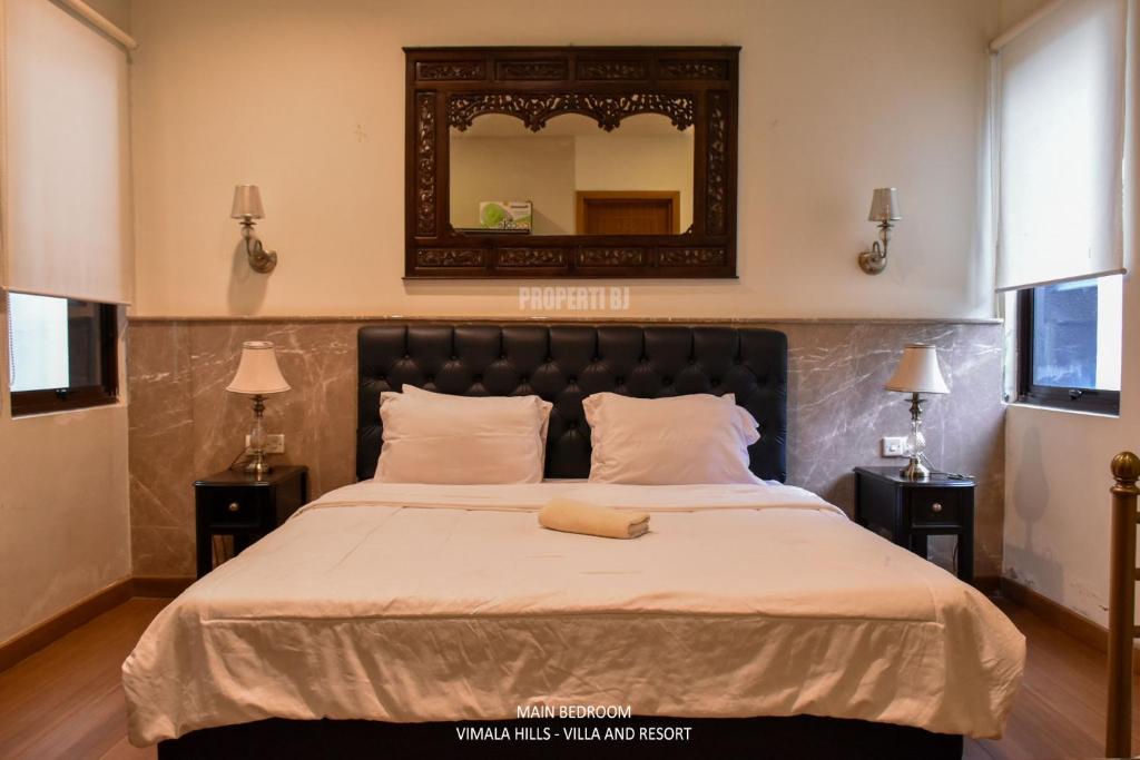 een slaapkamer met een groot bed met een spiegel aan de muur bij Vimala Hills Villa 2BR atau 3BR in Megamendung