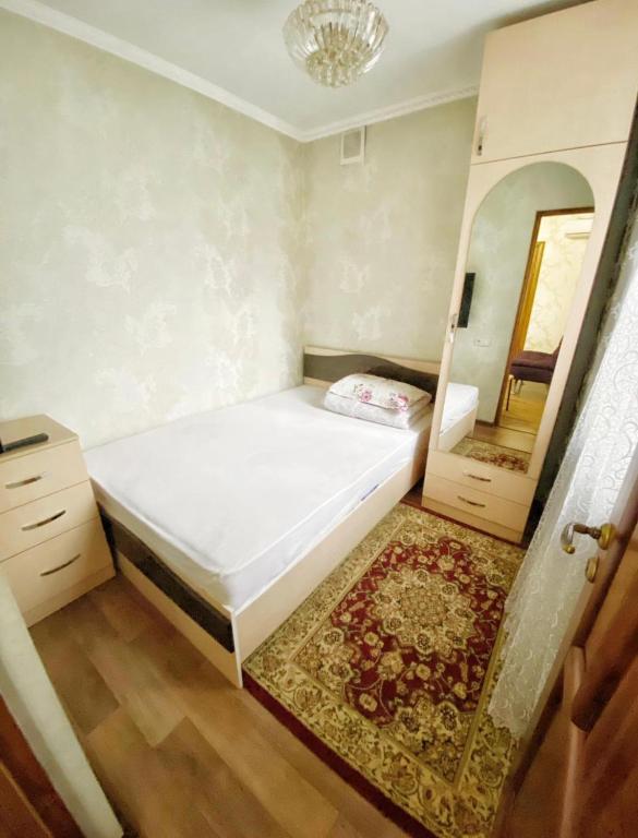 a small bedroom with a bed and a mirror at Apartments Ahmetova 4 21 in Almaty