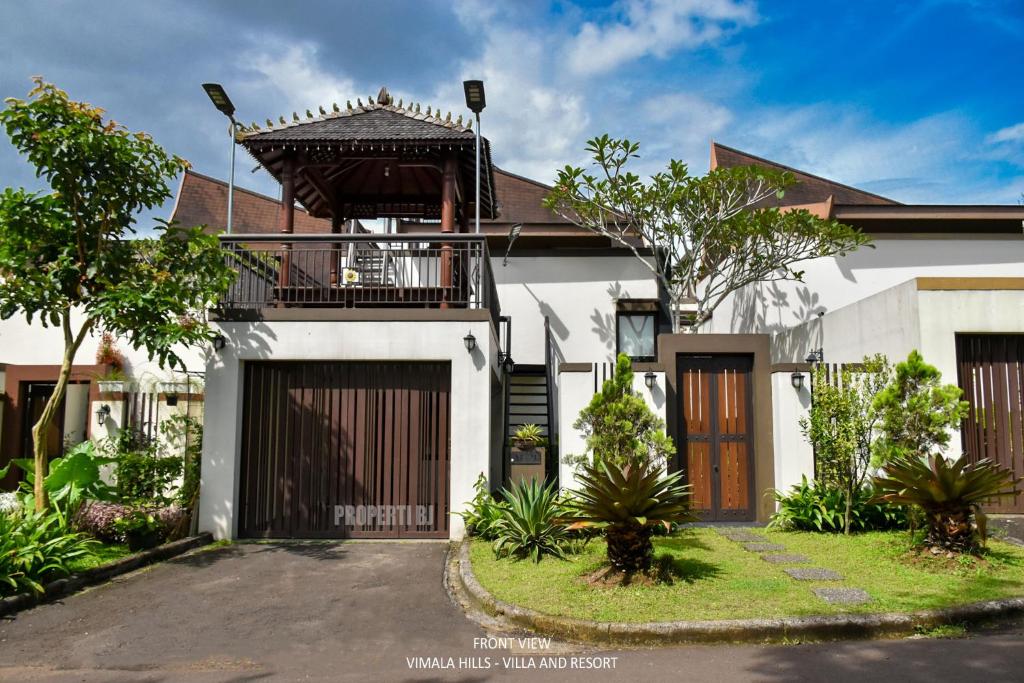 ein Haus mit einem Tor und einem Balkon in der Unterkunft Vimala Hills Villa & Resort in Megamendung