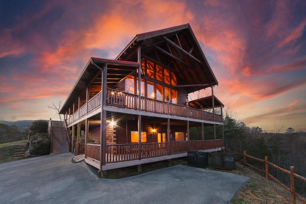a large wooden house with a sunset in the background at Heavenly Vista at Crown Point cabin in Sevierville