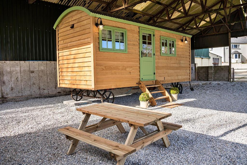 a tiny house with a picnic table and a bench at Finest Retreats - The Shepherd's Hut at Northcombe Farm in Beaworthy